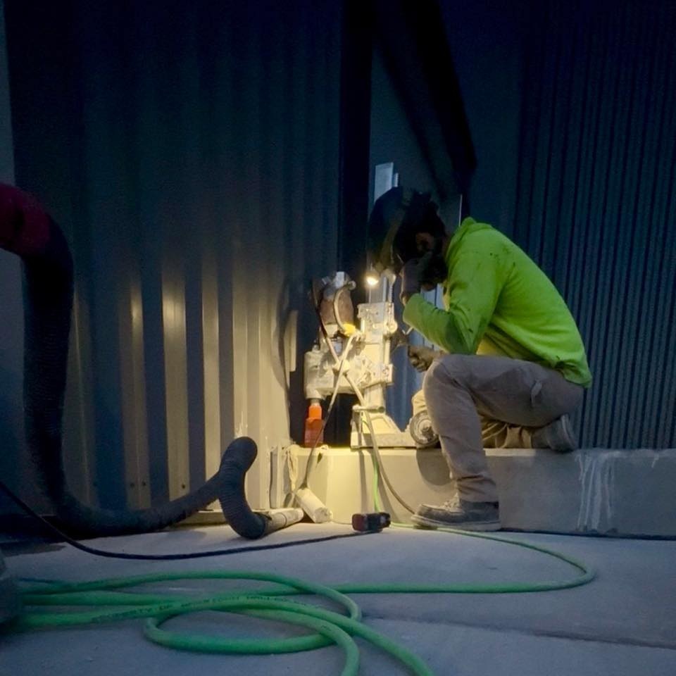 R&R Coring operator drilling at night with jobsite lighting